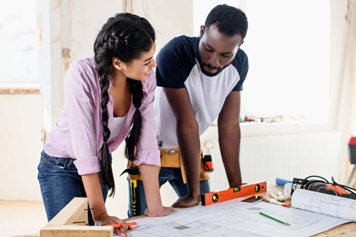 Couple reviewing renovation plans with tools on workbench